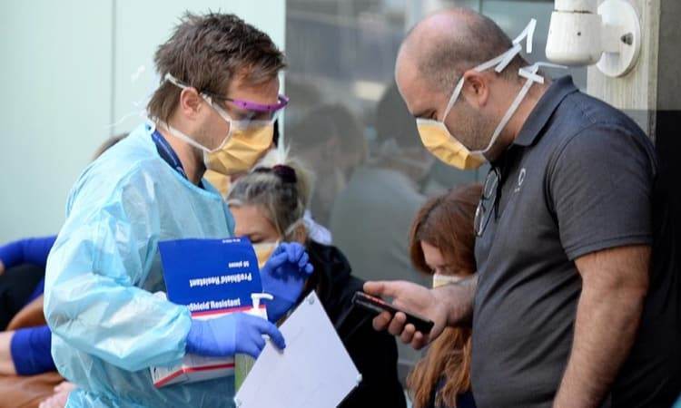 Nhân viên y tế nói chuyện với người đứng chờ xét nghiệm bên ngoài Bệnh viện Hoàng gia Melbourne hôm 10/3. Ảnh: Herald Sun.